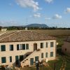 Un casolare in mattoni con tetto in tegole, immerso in un paesaggio di campagna.