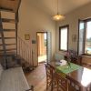 Interno con scala a chiocciola, tavolo, sedie e vista sulla piscina.