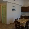 Cucina con tavolo, sedie, porte verdi e un quadro sul muro.