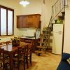 Interno di un appartamento con cucina, tavolo in legno, scale, divano e TV.