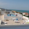 Area sul tetto con piscina, sedie a sdraio e vista sul mare.