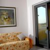 Salotto con divano fiorito, quadro di girasoli e porta finestra su un balcone.