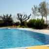 Piscina con sedie a sdraio colorate e alberi sullo sfondo.