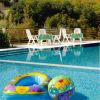 Piscina con giocattoli gonfiabili colorati e sedie bianche in legno.