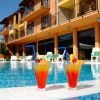 Due cocktail arancioni con cannucce blu su bordo piscina, hotel sullo sfondo.