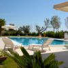 Piscina all'aperto con lettini bianchi, ombrelloni e vegetazione intorno.