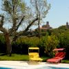 Una piscina con due sdraio colorate, alberi e un borgo sullo sfondo.