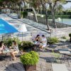 Persone sedute a tavolini all'aperto vicino a una piscina durante il giorno.